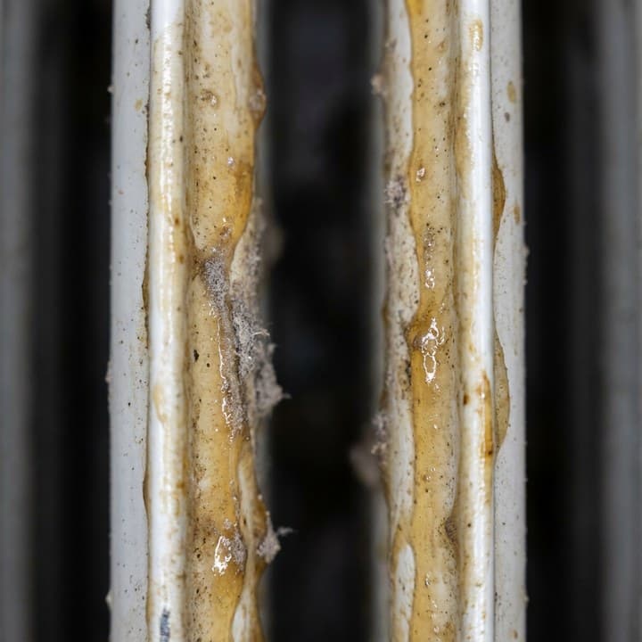 Makro detail — lepkavý mastný film na rebrách radiátora